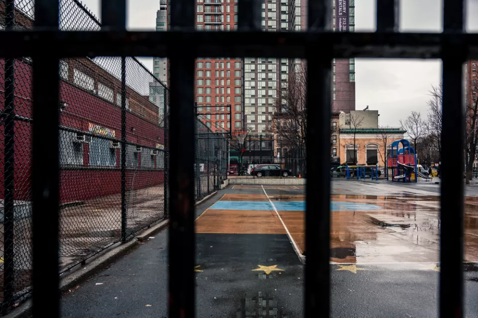 View of concrete schoolyard in New York City through fence